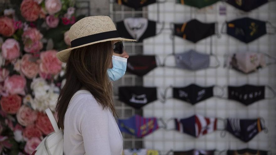 Una mujer paseando por la calle con mascarilla.