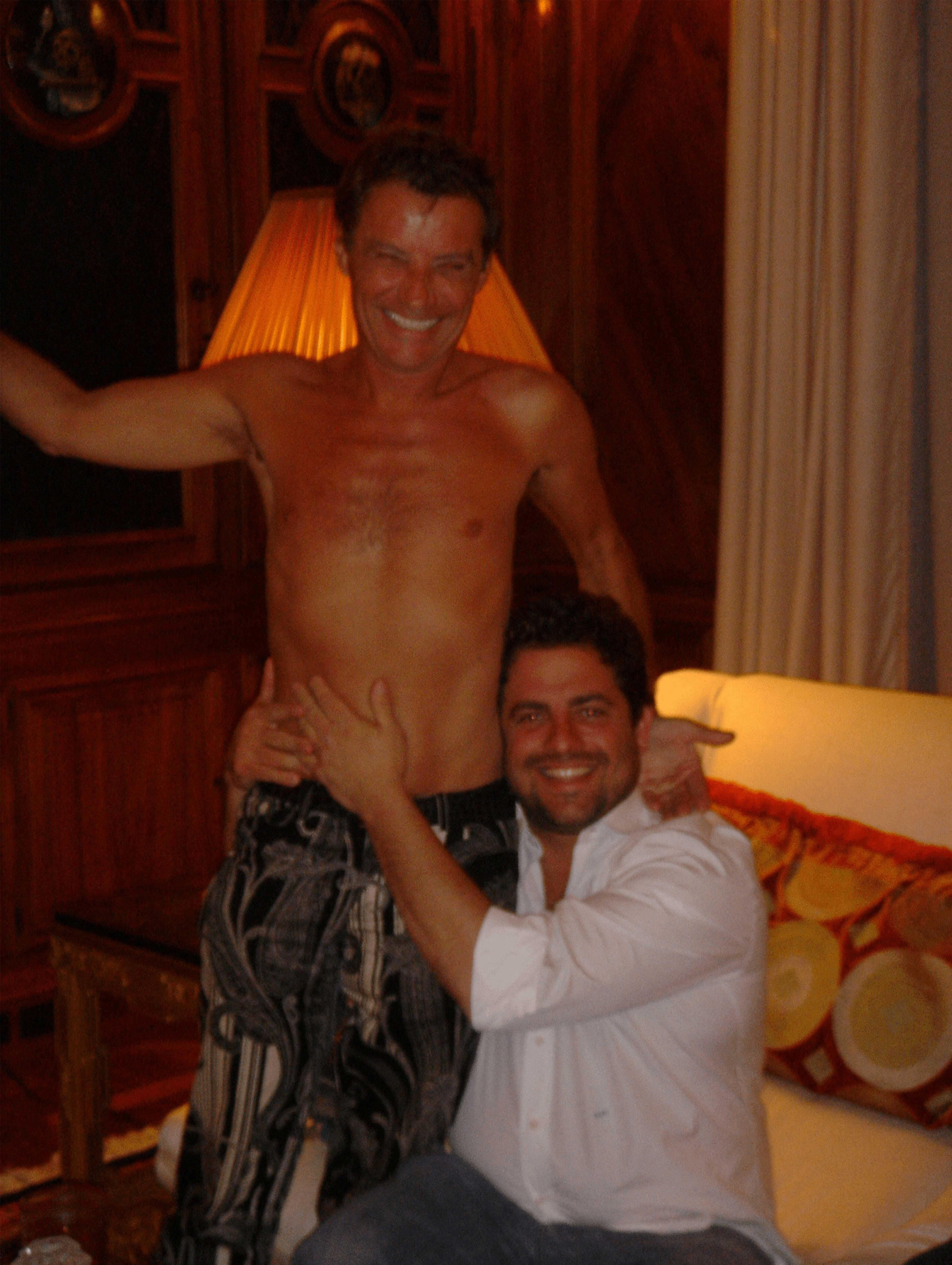 Jean-Luc Brunel, sin camisa, abrazado por Brett Rainer, de rodillas.