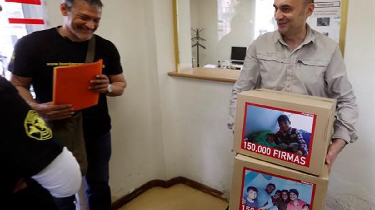 El representante de Bomberos en Acción Jorge Landete (i) entrega a un funcionario de la Secretaría General de Inmigración e Emigración más de 150.000 firmas para pedir al Gobierno que traslade a España con la mayor urgencia posible a Osman. | EFE