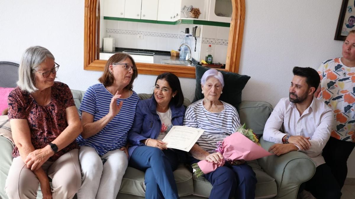 Constanza, de 102 años, recibe en el salón de su casa un diploma de Carolina Darias