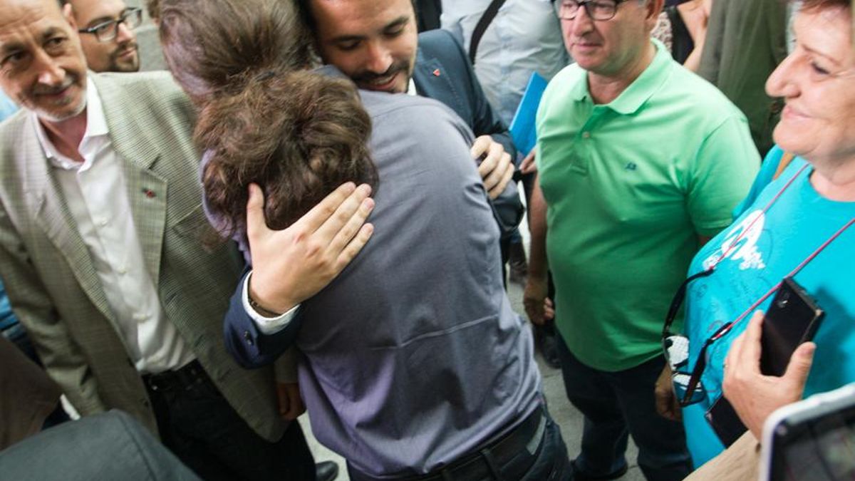 Pablo Iglesias (de espaldas) y Alberto Garzón se saludan durante la toma de posesión de Manuela Carmena. / Mariano Neyra