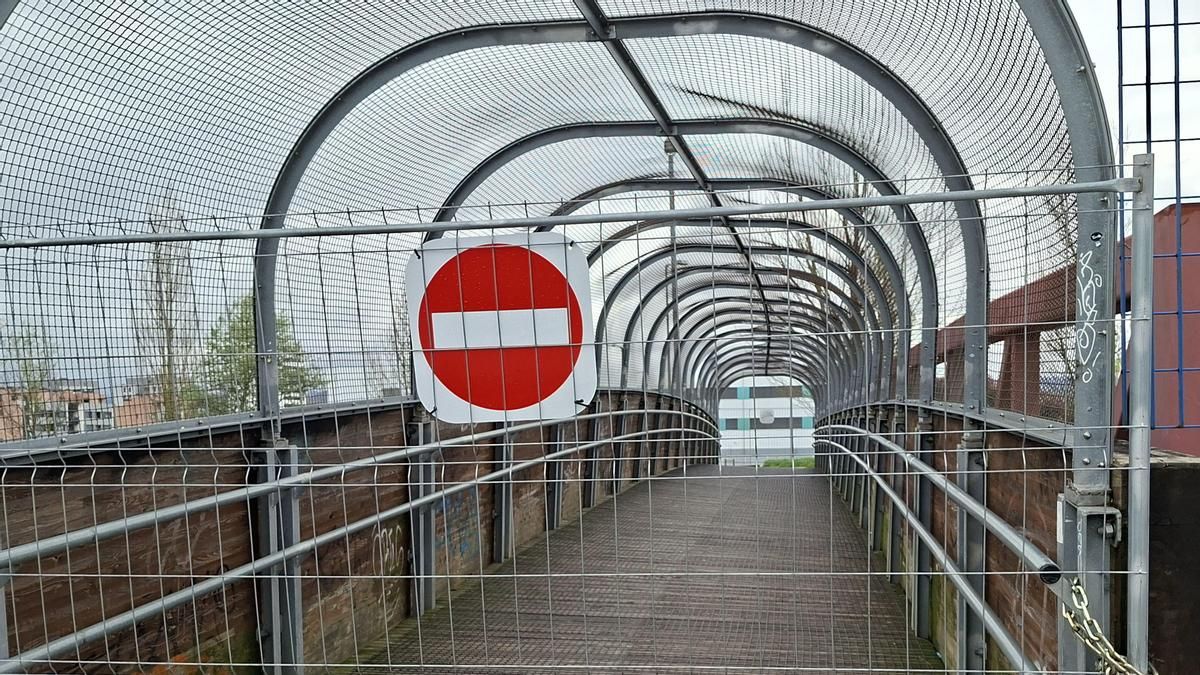 Barrera, asegurada con candados a la estructura, que impide el paso a la pasarela