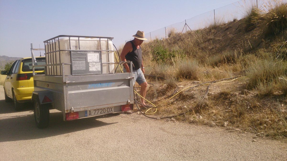 Otro vecino llenando su depósito de agua en una balsa para llevarla a casa