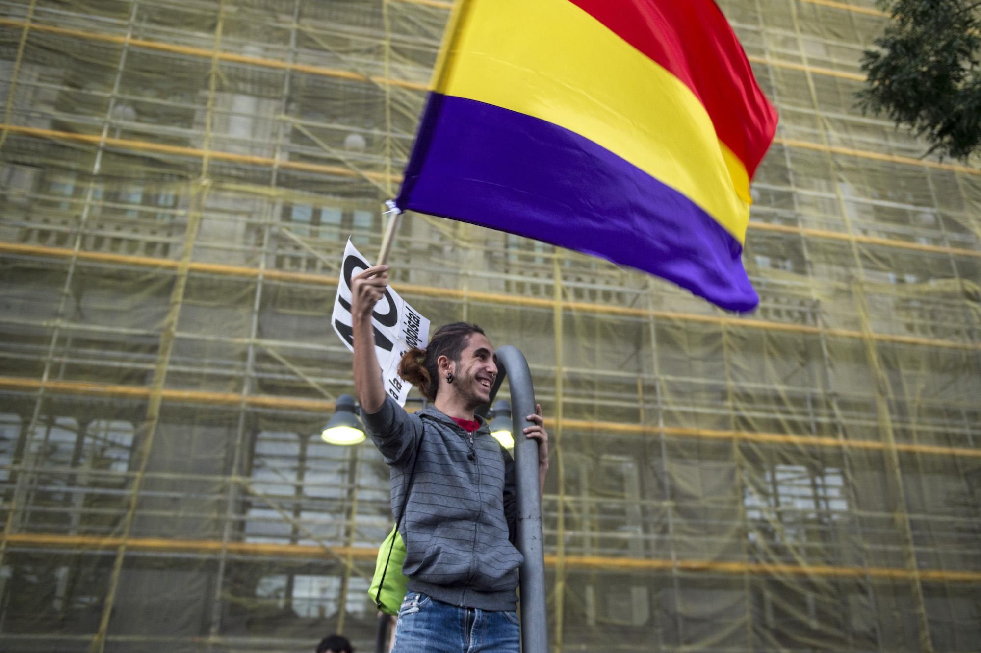 Un joven manifestante ondea una bandera republicana frente al edificio del Banco de España, durante la manifestación "rodea el Congreso"