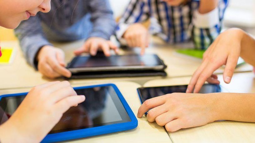 Imagen de archivo de varios niños utilizando tabletas digitales en un aula