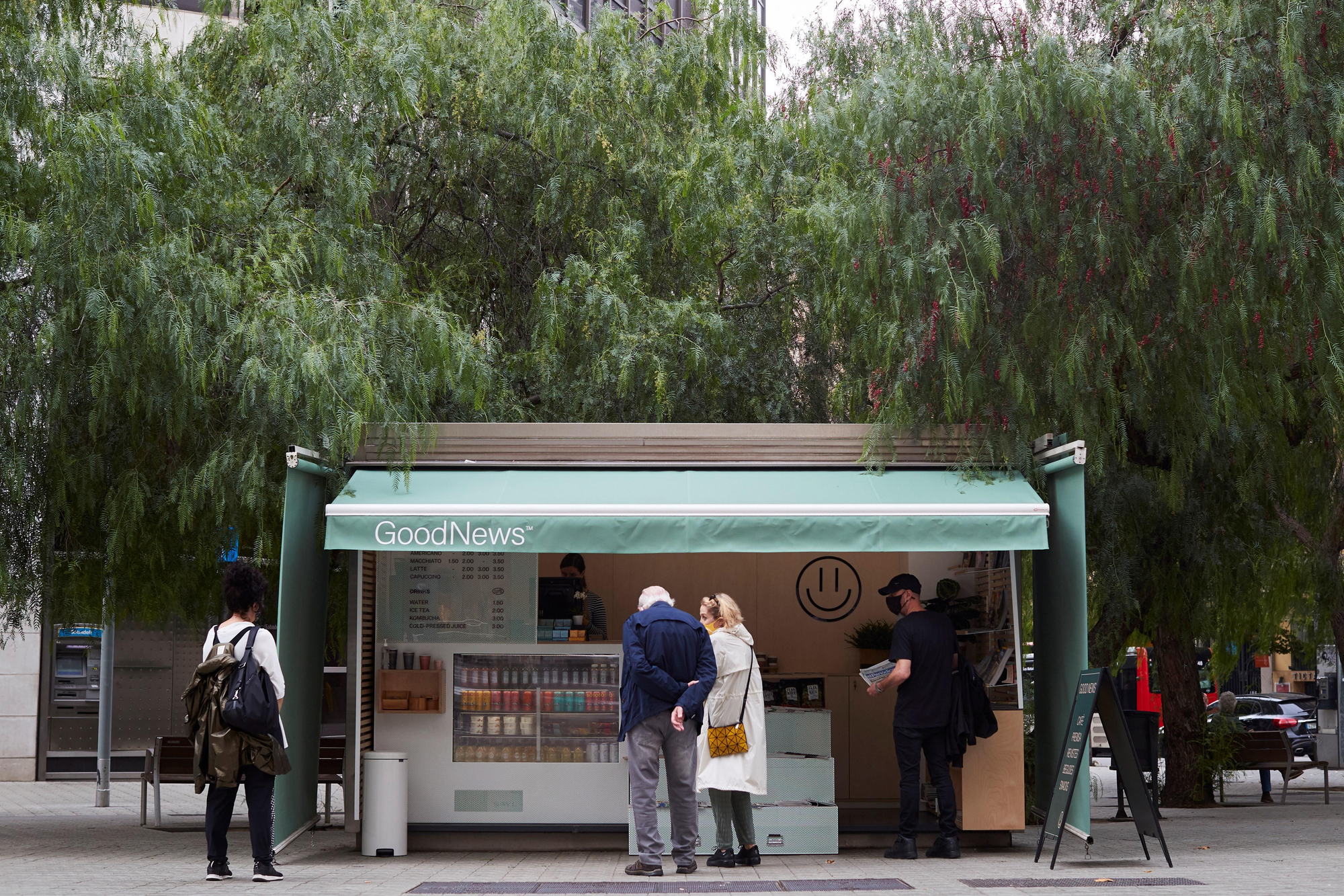 Clientes ojean las ofertas de uno de los quioscos de Barcelona reconvertidos de la mano de 'Good News'