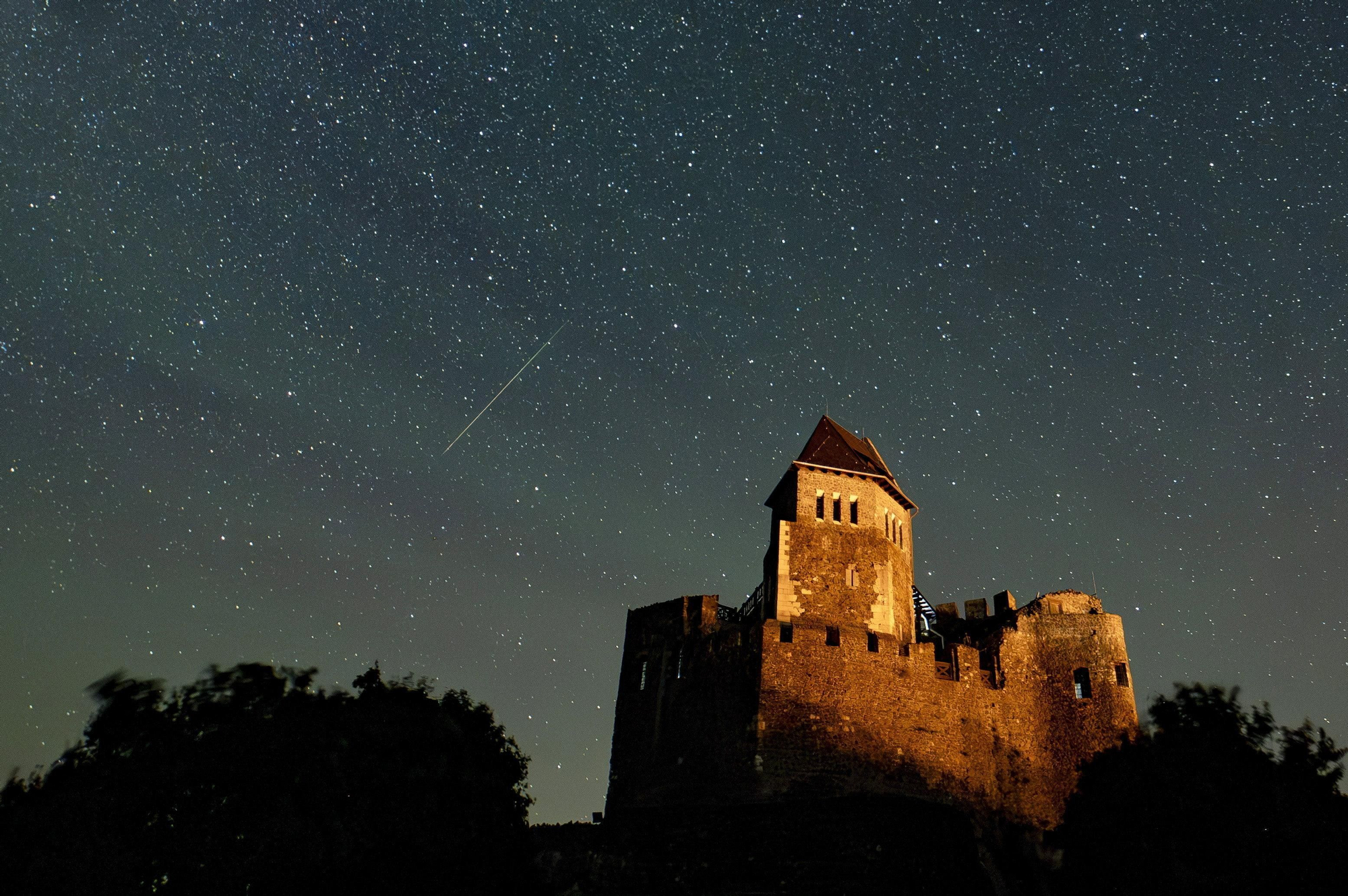 Fotografía de larga exposición con una estrella fugaz durante la lluvia de perseidas sobre el castillo de Holloko, Hungría, este domingo EFE/EPeter Komka