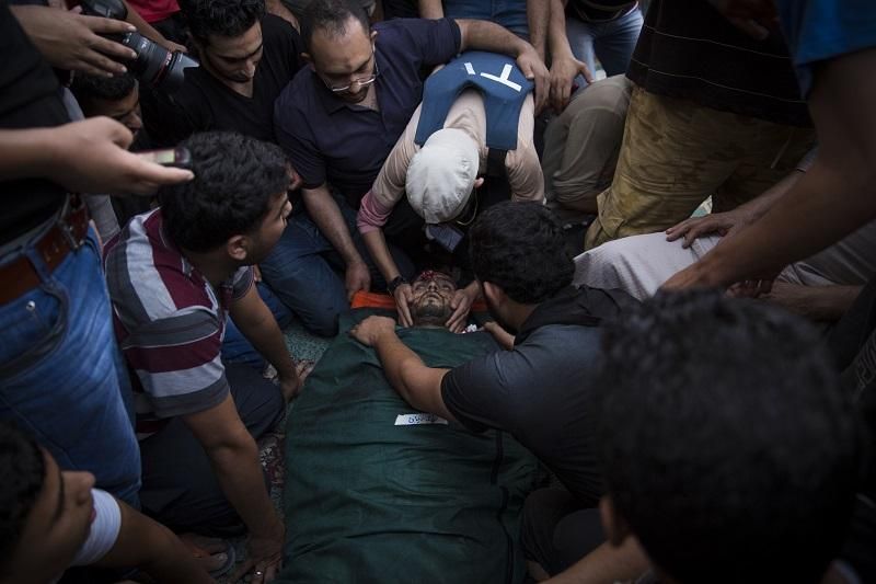 Varias personas atienden al periodista de 24 años fallecido en los ataques al supermercado del oeste de Shujaeya, en Gaza. FOTO:  Juan Ramón Robles