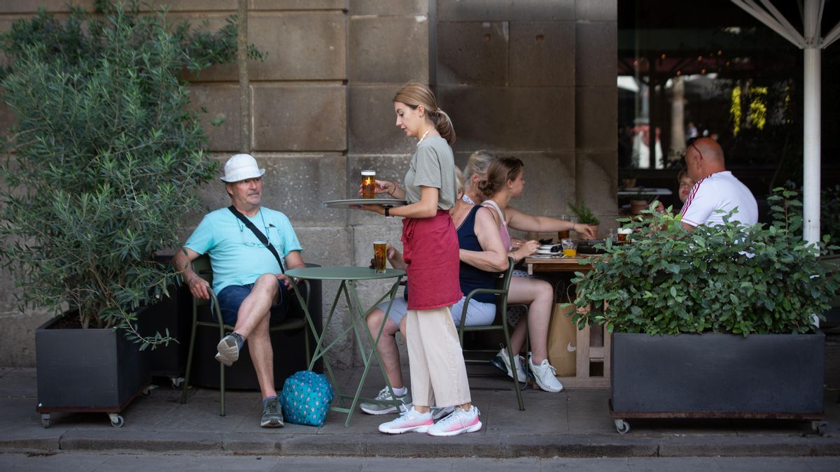 Una empleada de hostelería sirve a un cliente en la terraza
