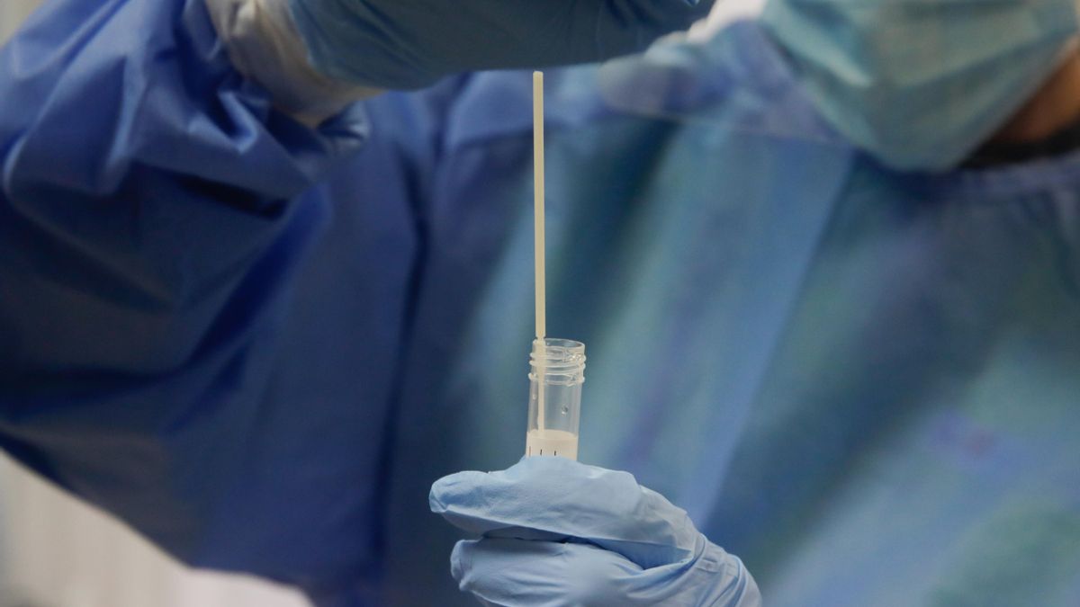Una trabajadora sanitaria sostiene una probeta con una prueba PCR