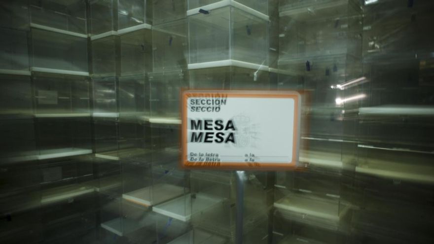 Detalle de un cartel ante urnas preparadas para unas elecciones.