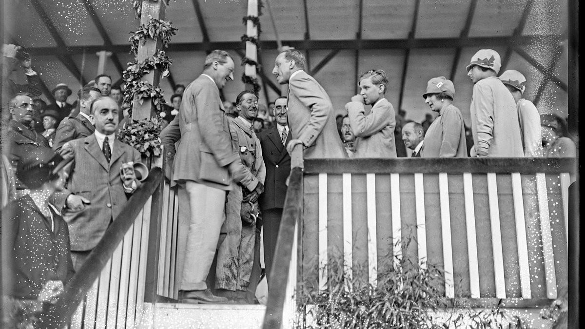 El rey Alfonso XIII, felicitando a Ettore Bugatti, fundador de la casa del mismo nombre, y al ganador, Goux, en la tribuna de autoridades