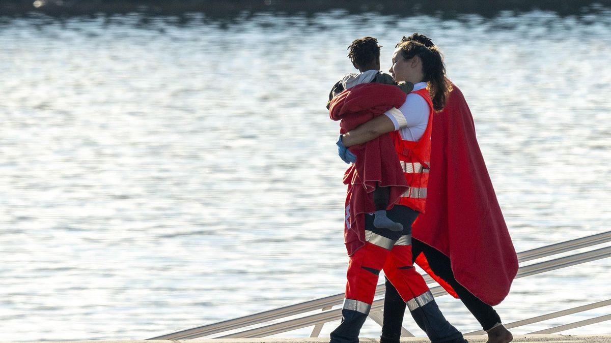 Una trabajadora de la Cruz Roja lleva en brazos a un bebé llegado a bordo de una patera