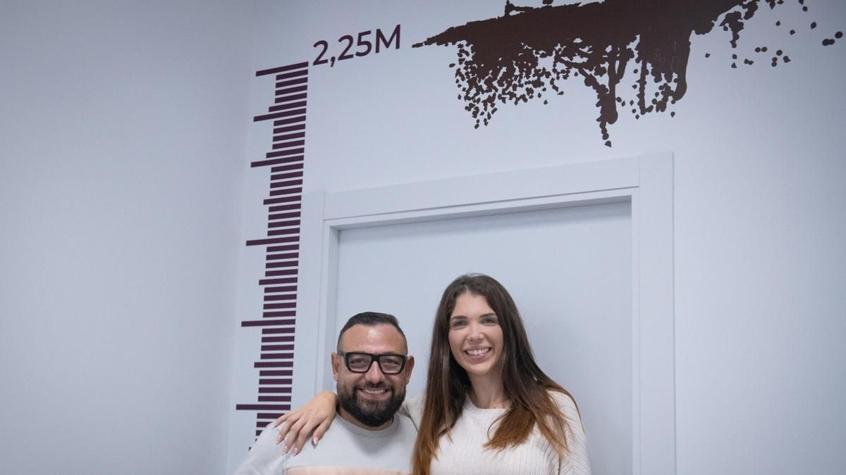 Miguel and Sandra in their real estate agency, next to the mark that remembers where the mud arrived