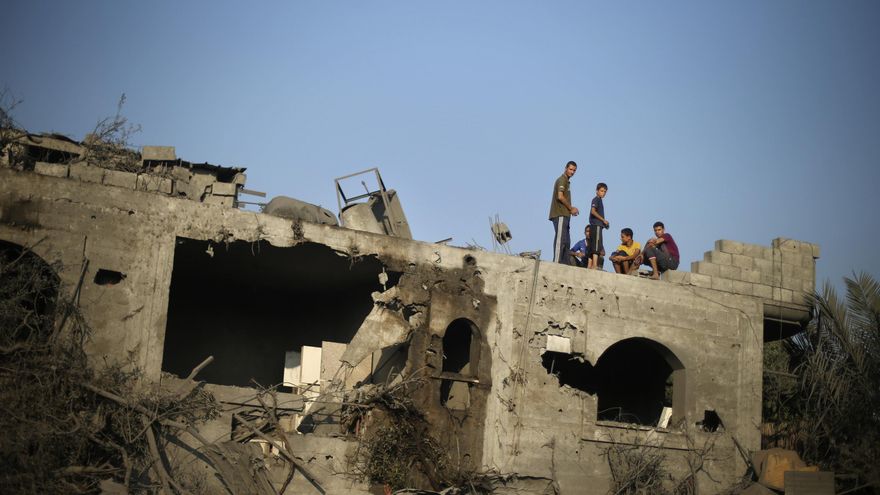 Palestinos junto a los restos de una casa dañada tras uno de los ataques israelíes en Gaza