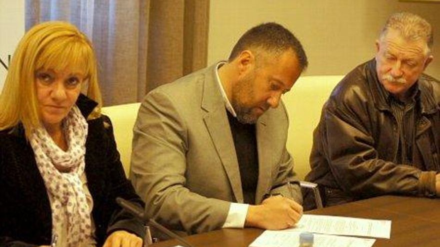 Carlos Pollán firma el convenio, Jesús Fernández espera a la derecha e Isabel Carrasco a la izquierda.