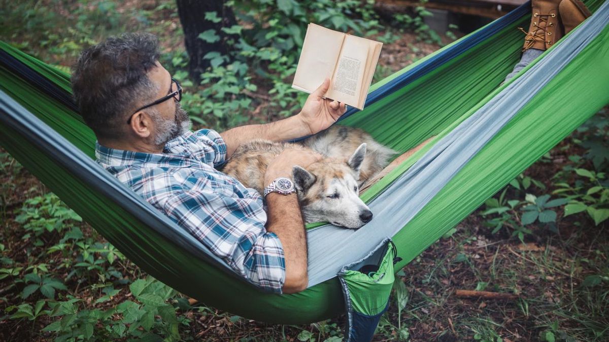 Un hombre lee un libro junto a su perro