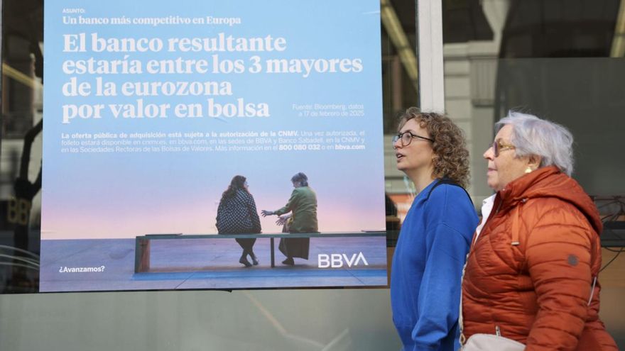 Dos mujeres pasean delante de una cartel del BBVA y el Banco Sabadell que defiende la OPA.