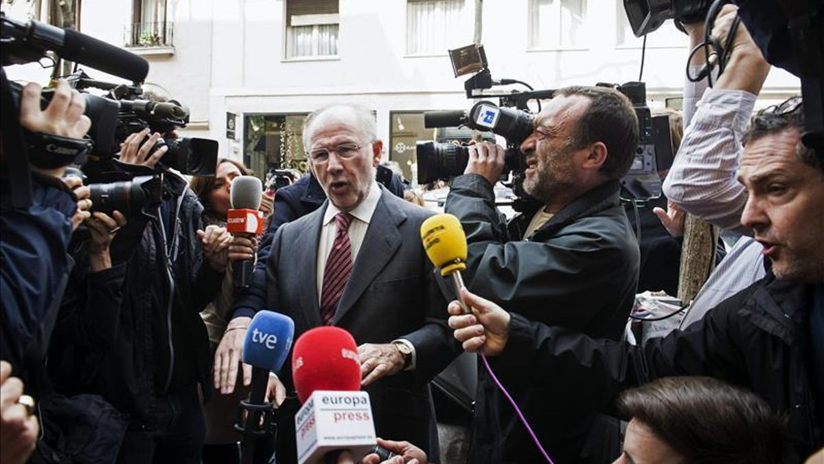 Rodrigo Rato, rodeado de cámaras, llega a su despacho para presenciar el registro.
