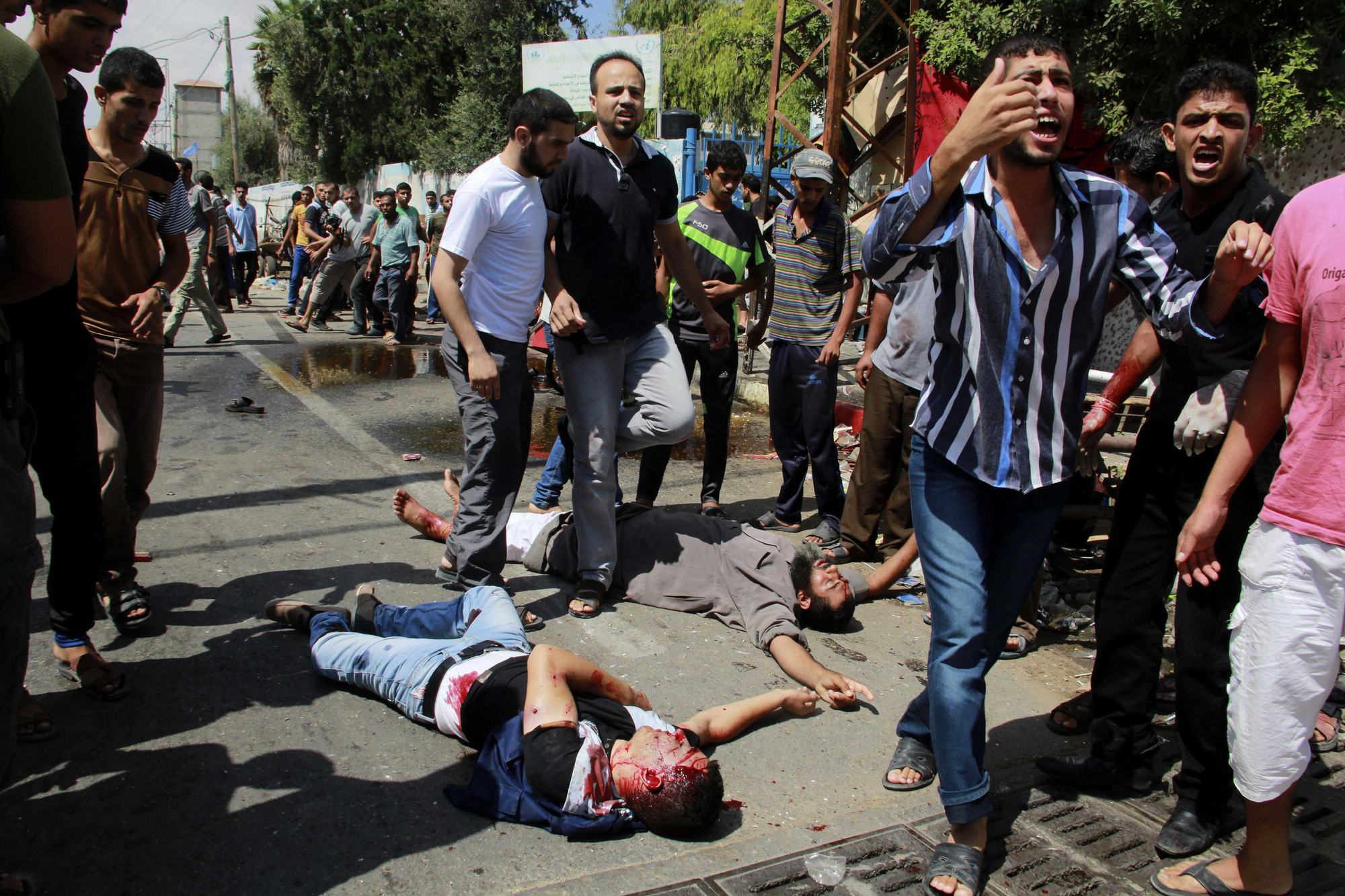 Palestinos muertos y heridos en los alrededores de la escuela de la ONU bombardeada por Israel este domingo, rodeados de varios palestinos / Hatem Ali \ AP Photo