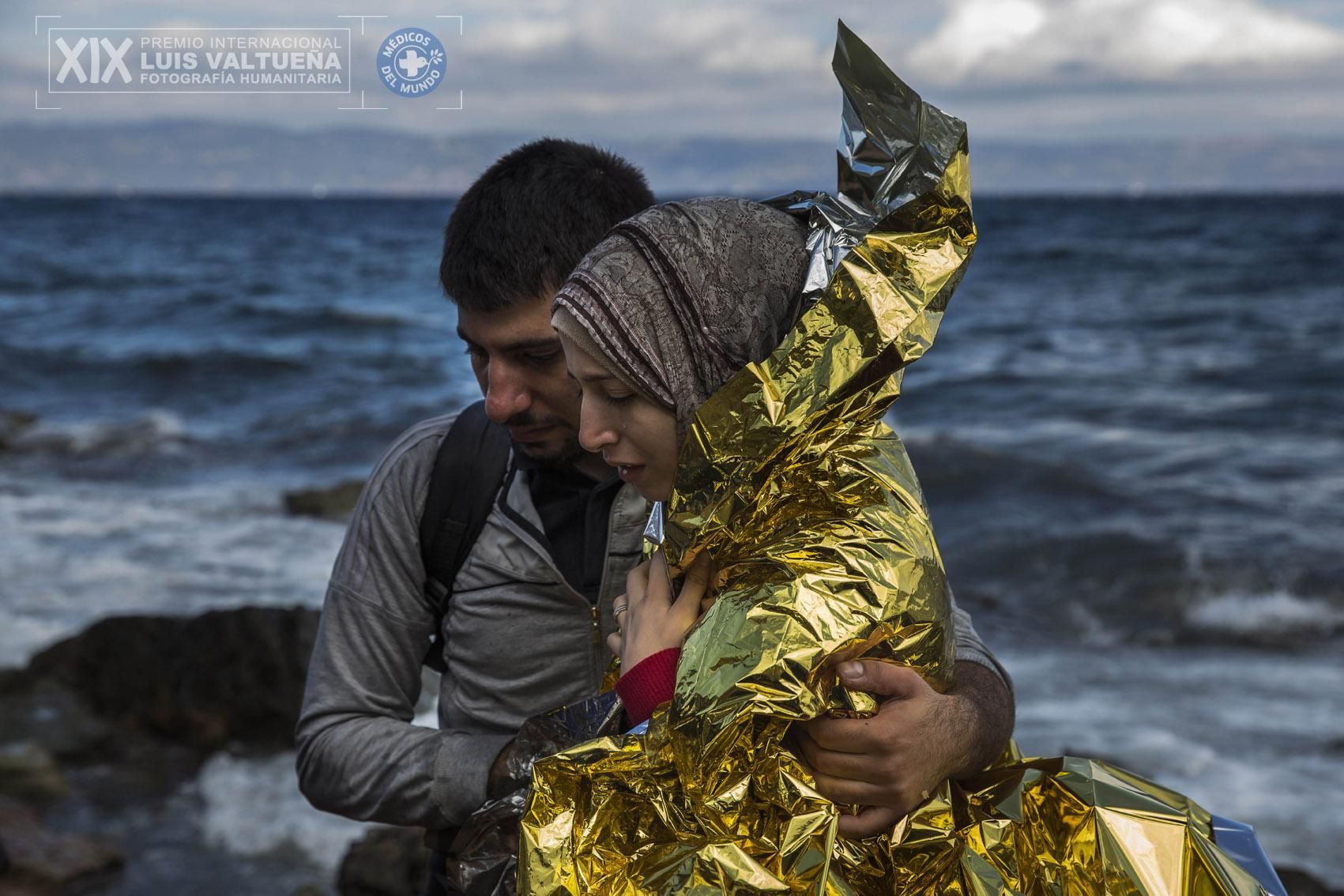 Más de un millón de personas ha llegado a Europa arriesgando su vida en el Mediterráneo en 2015, según los datos de Acnur. Muchos, como los protagonistas de esta fotografía, vienen huyendo de la guerra siria y alcanzan Grecia en precarias embarcaciones por lsa que pagan enormes cantidades de dinero a traficantes de personas en Turquía. La serie 'Miles de vidas en juego para llegar a Europa', del madrileño Santi Palacios, captura el desembarco en Lesbos y le ha valido el puesto de segundo finalista en el premio internacional de Fotografía Humanitaria Luis Valtueña. Esta pareja de jóvenes sirios ha conseguido sobrevivir al viaje. | Foto: Santi Palacios.
