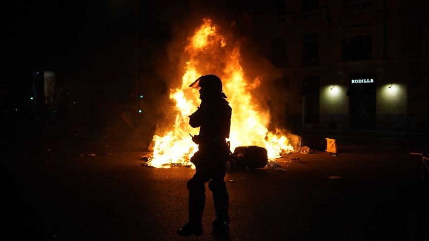 Un policía junto a un contenedor en llamas tras las cargas de este 9 de noviembre en Ferraz.