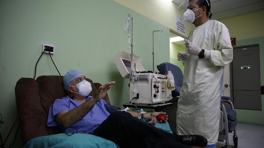 Fotografía realizada el 30 de junio de 2020, de un donante que conversa con Jaime Alfaro (d), director del banco de sangre del hospital Benjamín Bloom en San Salvador.