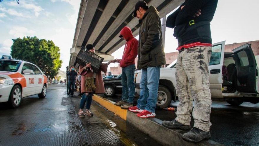 Personas de la ciudad de Tijuana, en el estado de Baja California, reparten un poco de comida a migrantes estacionados en esta zona fronteriza de México.
