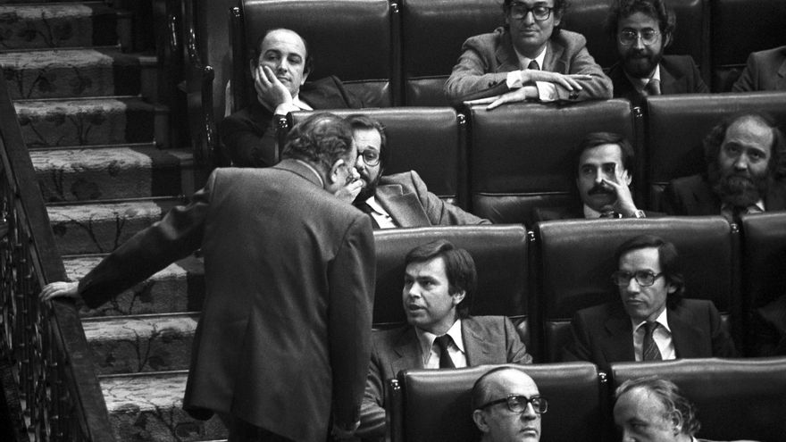 El secretario general del PSOE, Felipe González, sentado en su escaño, conversa con Santiago Carrillo, durante el debate de moción de censura.