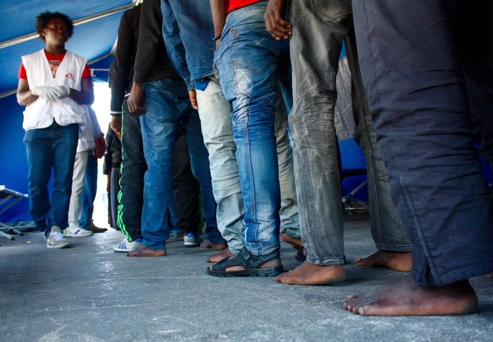 Antes de su ingreso en el centro de recepción primaria de Pozzallo, refugiados, migrantes y solicitantes de asilo pasan un triaje y un examen médico. Moussa, mediador cultura de MSF, está presente en el proceso. MSF trabaja en Pozzallo facilitando atención médica para los recién llegados en colaboración con Ministerio de Salud de Italia. Fotografía: Alva White/MSF