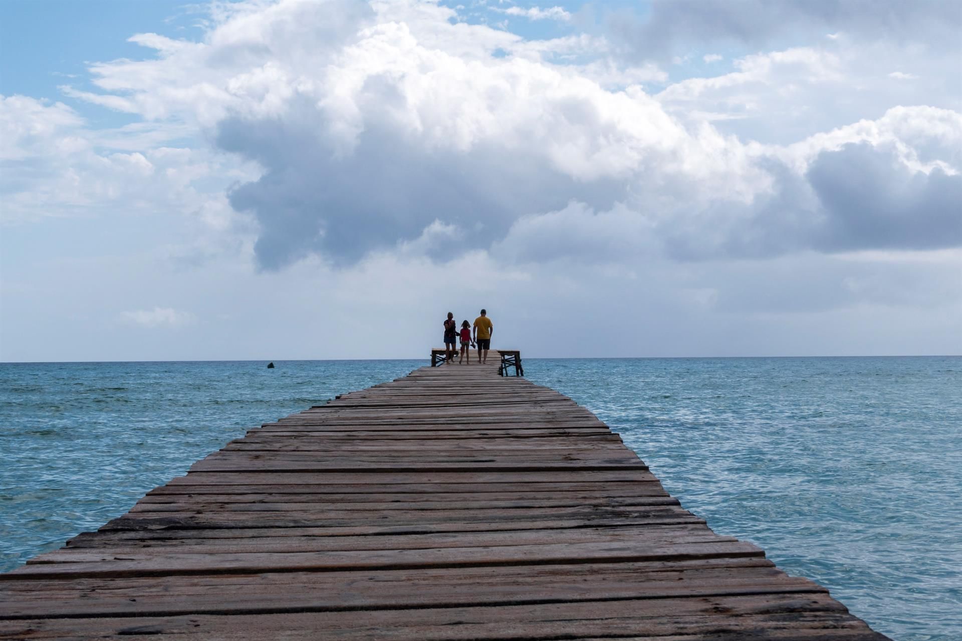 Una família passeja per un espigó a la Platja d'Alcúdia (Mallorca) el juny de 2020