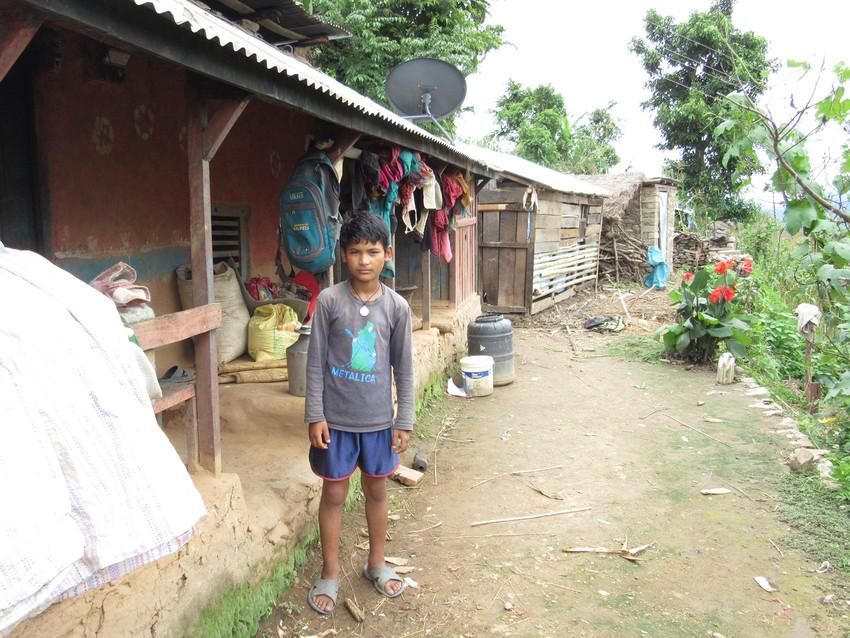 Nirjan, de doce años, sonríe frente a su antigua casa derruida por el terremoto. Asegura que ya no tiene miedo a estos fenómenos tras haber leído en su libro de Ciencias por qué se producen. Antes del terremoto del 24 de abril la mayoría de los niños en Nepal no sabían lo qué eran estos fenómenos. Foto: Save the Children