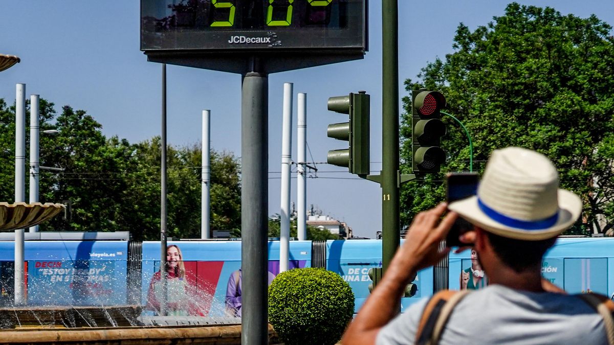 Transeúntes fotografían el termómetro situado en el Prado que marca 50 grados.