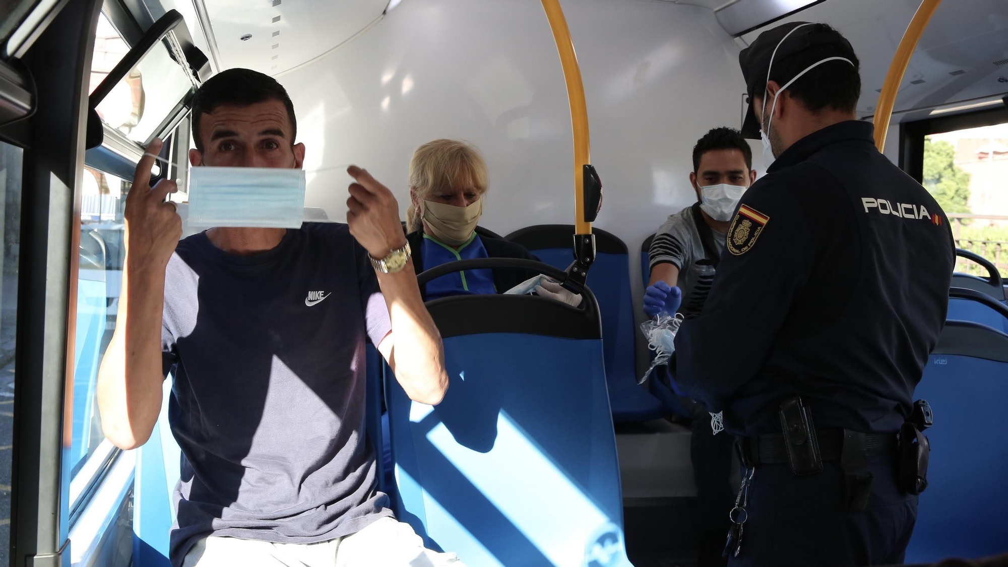 Un agente de Policía entrega mascarillas a los pasajeros de una guagua. (Alejandro Ramos)