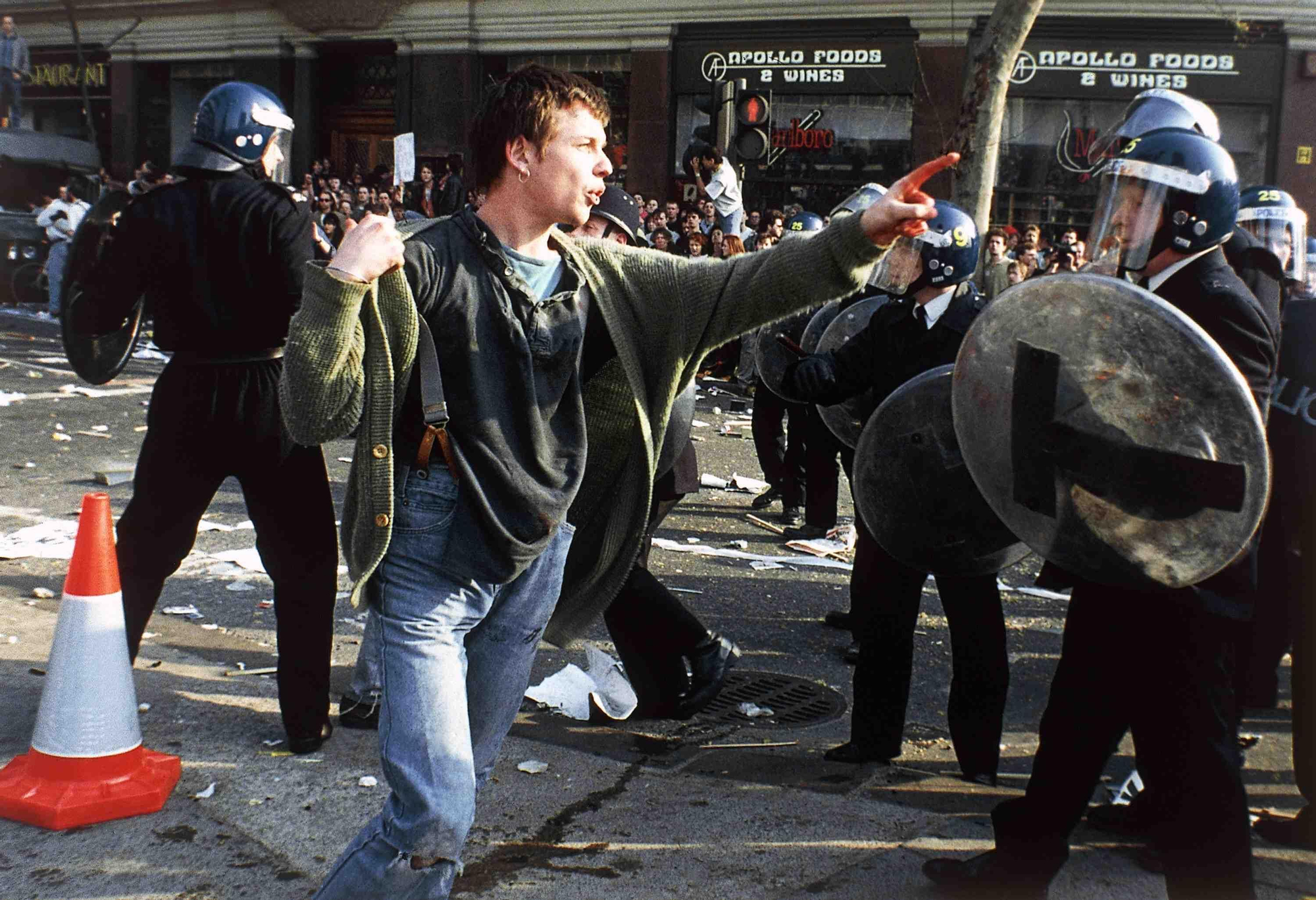 An anti-Poll Tax (Community Charge) protester faces police in riot gear in London's Trafalgar Square, United Kingdom on March 31, 1990 after a protest march against the new Community Charge turned to violence. Buildings were set alight and police made dozens of arrests. (AP Photo/Martyn Hayhow)