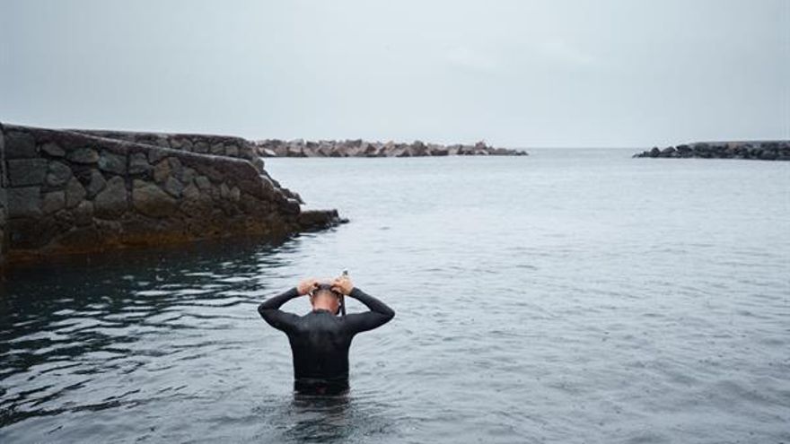 Un hombre se prepara para bañarse bajo la lluvia en la zona costera del barrio de San Andrés, en Santa Cruz de Tenerife. (EFE/Ramón de la Rocha)