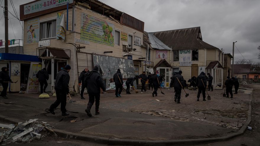 Un grupo de hombres hace trabajo de limpieza en una calle aledaña a un edificio que sufrió daños tras un ataque con artillería pesada, en Borodianka (Ucrania). EFE/ Miguel Gutiérrez