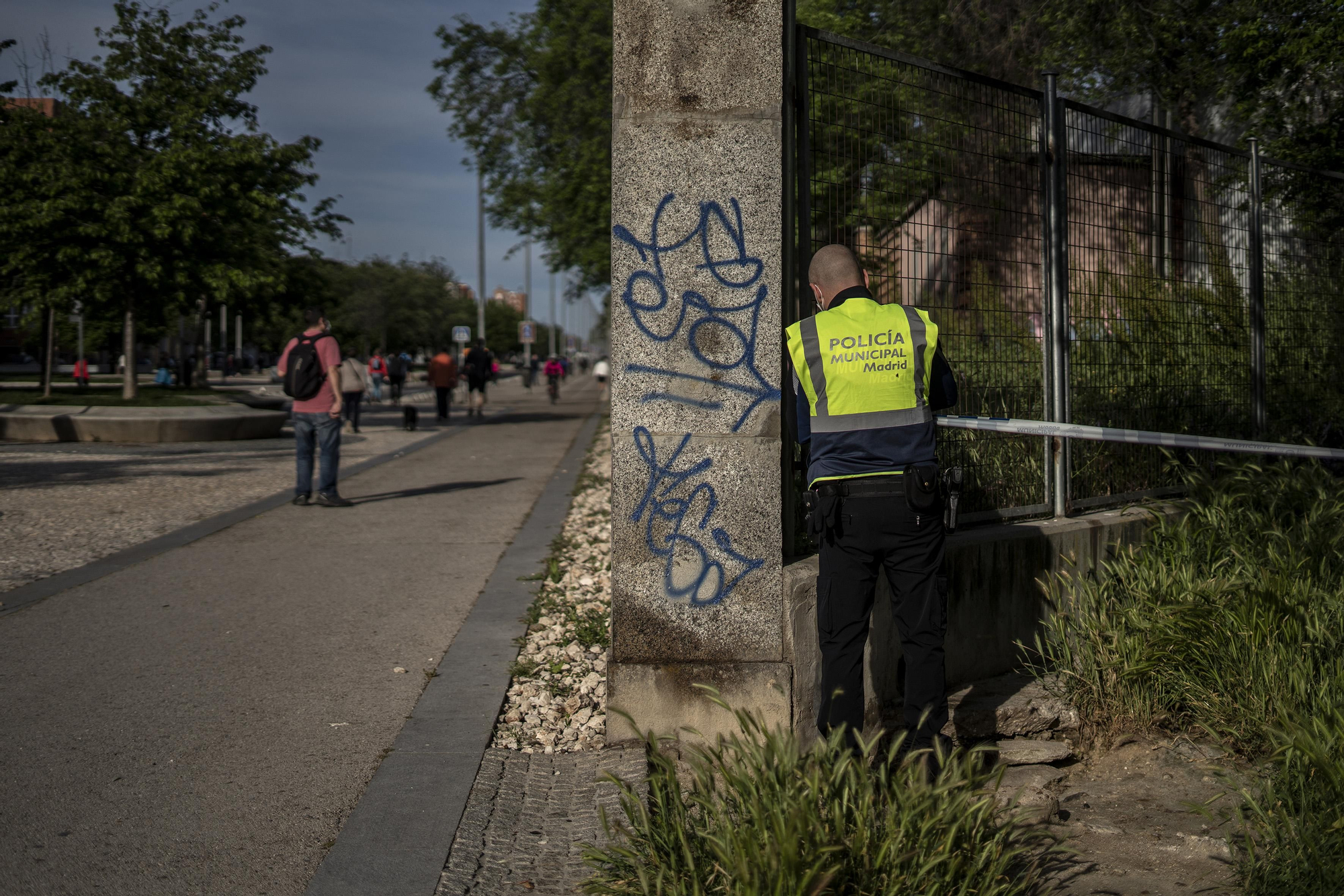 Un policía municipal coloca una cinta policial que alguien había arrancado para entrar en la Casa de Campo