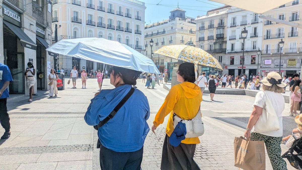 Dos mujeres se protegen del calor con paraguas bajo los toldos de la Puerta del Sol