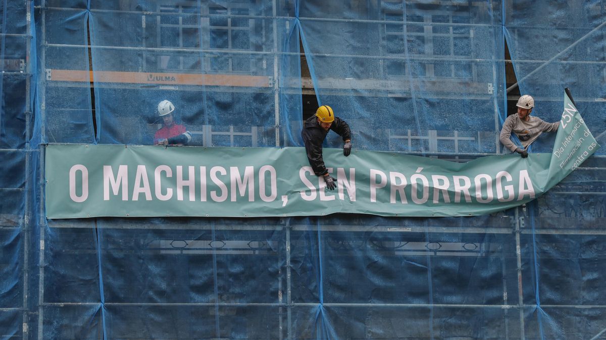 Imagen de archivo de tres obreros colocando una pancarta alusiva al machismo, 'El machismo, sin prórroga', en Santiago.